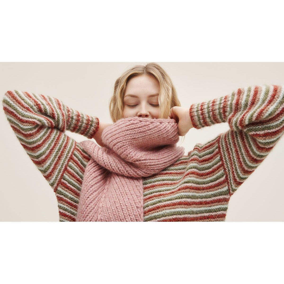 Woman wearing knitted sweater in garter stitch stripes of dark red, coral pink, white and dark green (01 Erika)