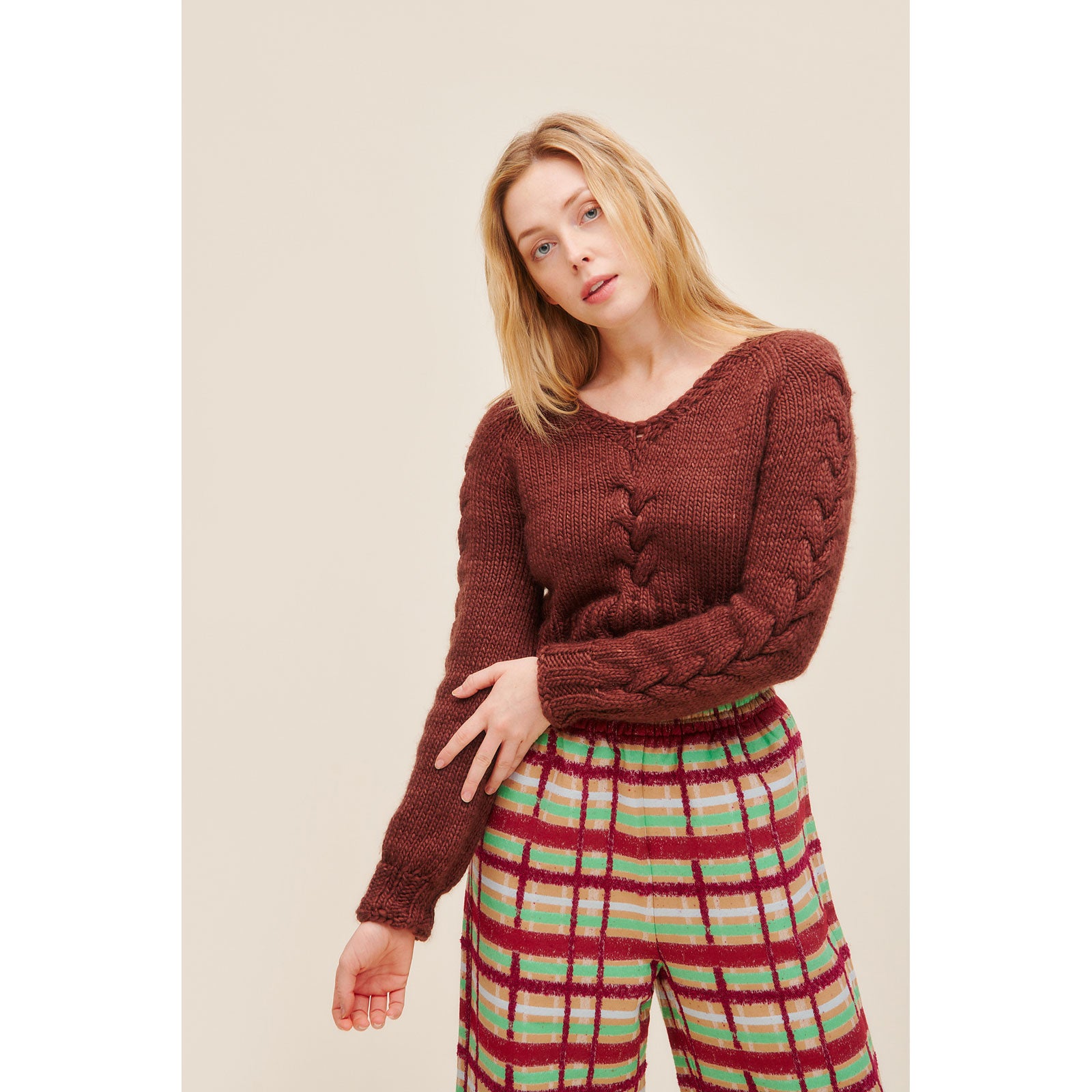 Woman wearing a knitted warm brown coloured crop sweater with cable detail centre back of each sleeve and centre front (12 Victorine)