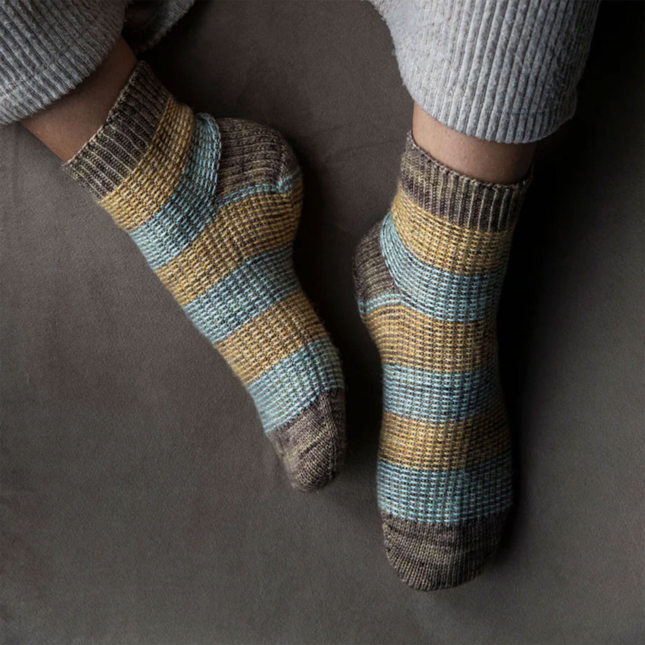 Striped textured socks worn by a person on a dark background