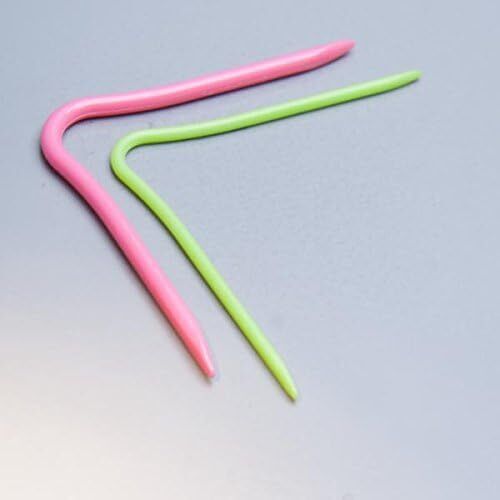 Two colourful cable needles, one pink and one green, on a grey background.