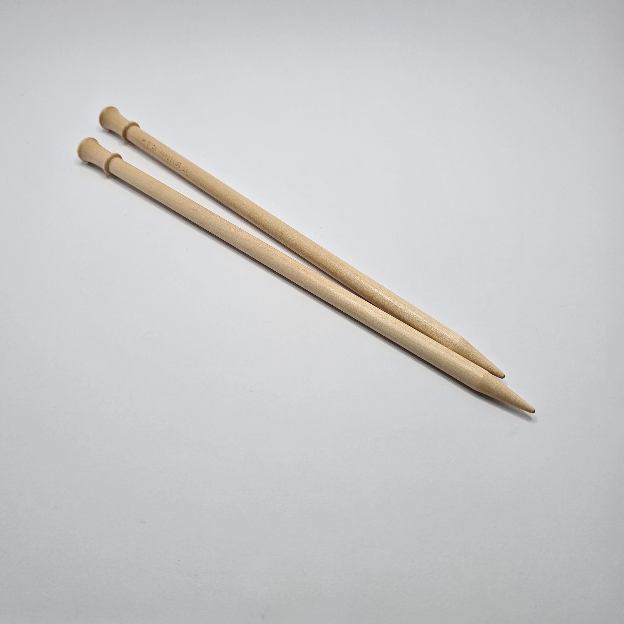 Pair of Brittany birch wood knitting needles on plain background