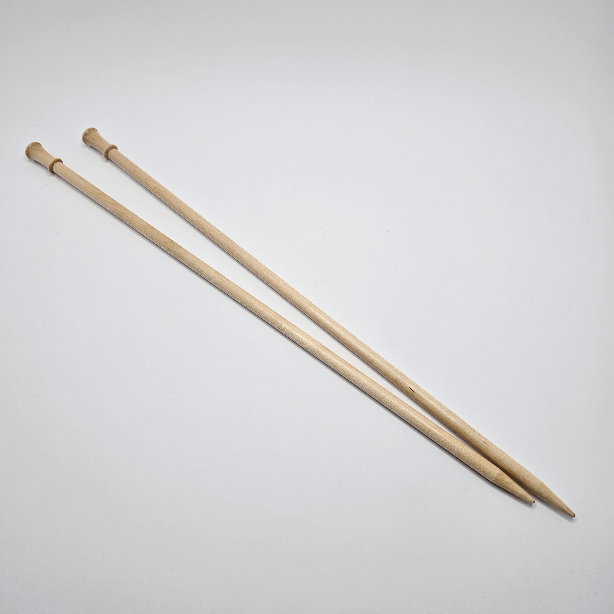 Pair of Brittany birch straight knitting needles on a plain background