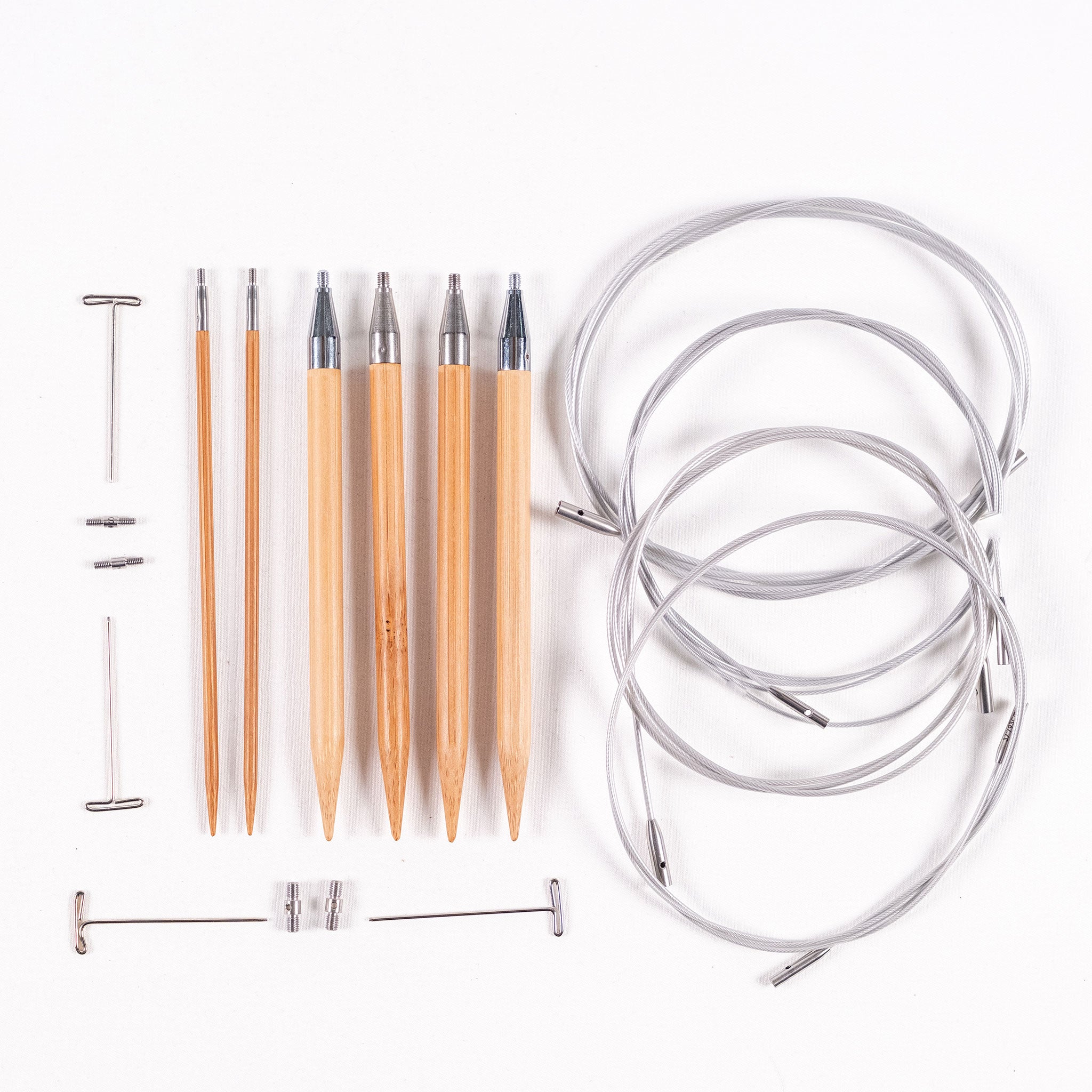 Three pairs of ChiaoGoo 5in long SPIN bamboo interchangeable knitting needle tips in sizes 3mm, 7mm and 7.5mm, four tightening keys, two small and two large cable connectors, and four SWIV360 silver interchangeable cables with lifeliine holes