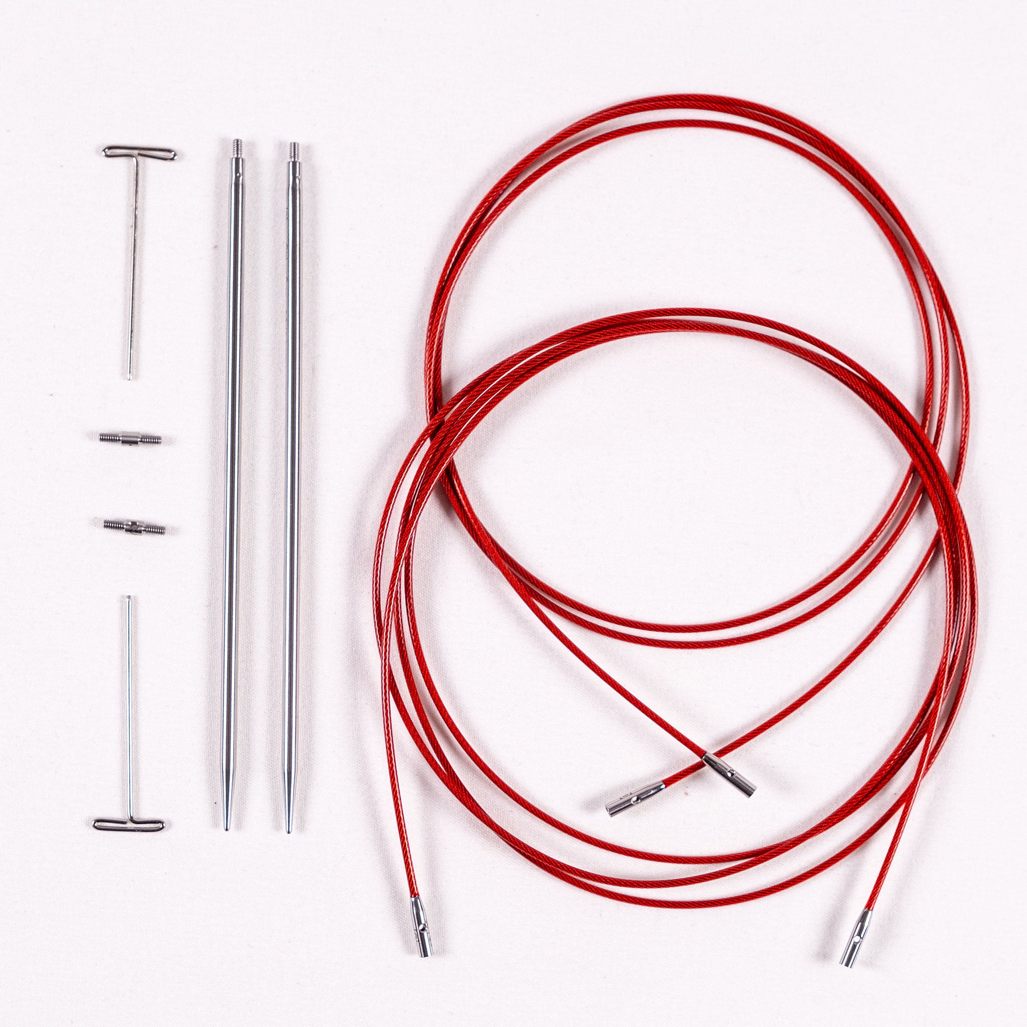 Pair of ChiaoGoo 3mm stainless steel interchangeable knitting needle tips, two tightening keys, two small cable connectors, one 37in and one 50in red lace cable, coiled on a white background
