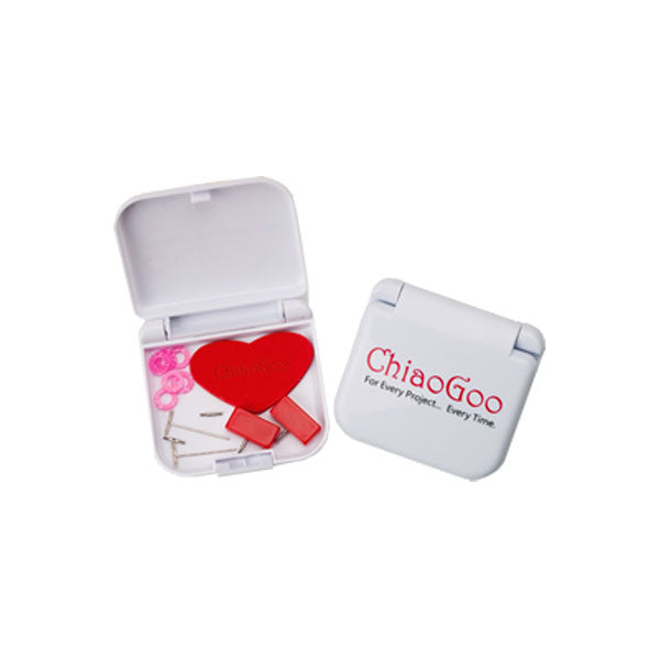 White plastic click shut container lying open showing contents of pink stitch markers, red heart, mini t-pins, red min end stoppers and two mini cable connectors. On right hand side is closed storage case with red ChiaoGoo logo and black text "For Every Project... Every Time."