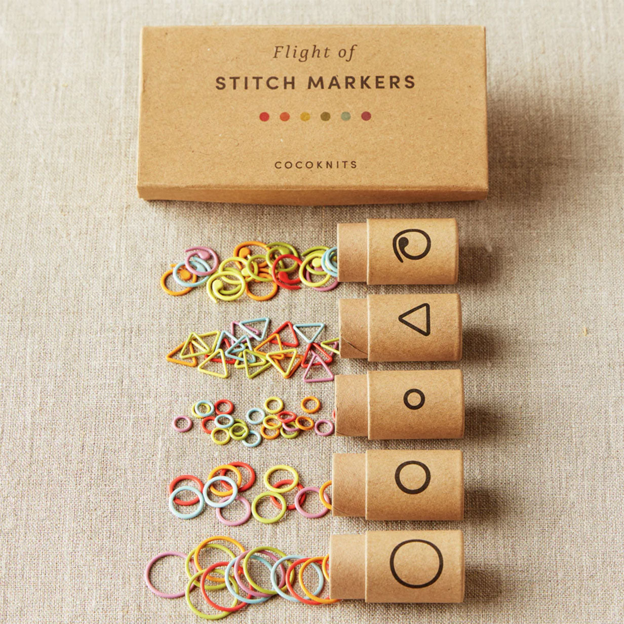 Cocoknits stitch markers with cardboard packaging on linen background
