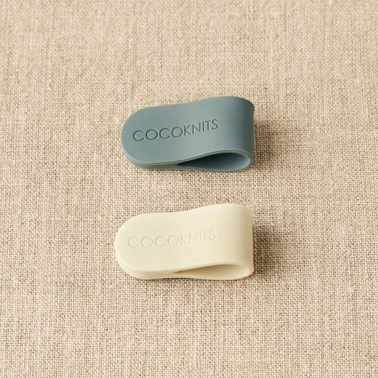 Cocoknits magnetic clips, one grey, one cream on linen background