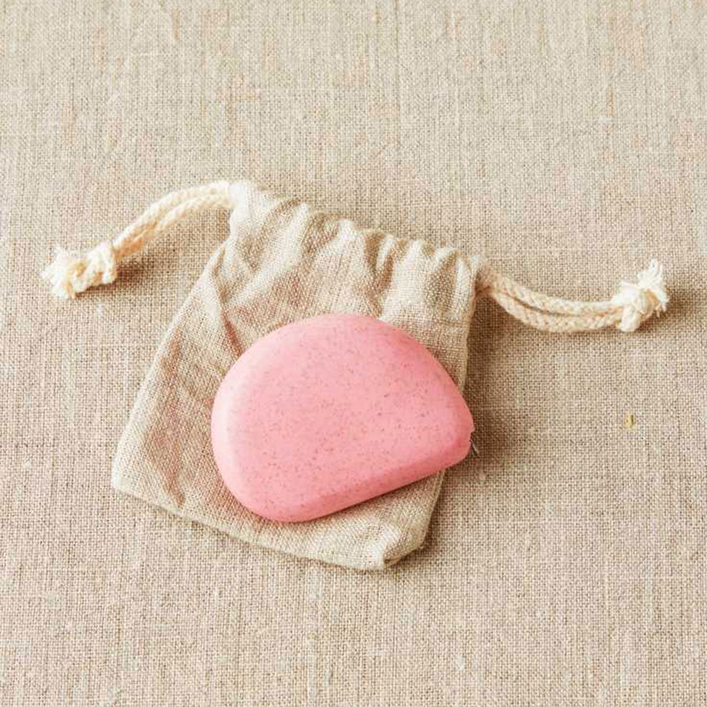 Pale pink coloured pebble shaped tape measure on linen drawstring bag