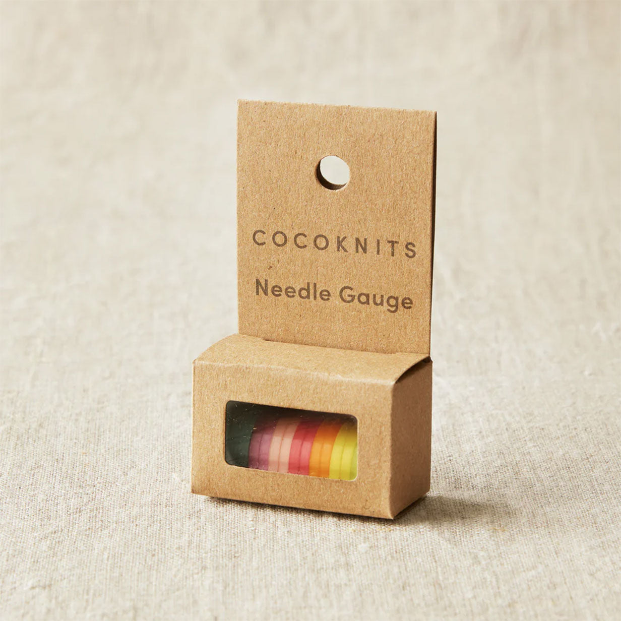 Cocoknits needle gauge packaging on a beige fabric background