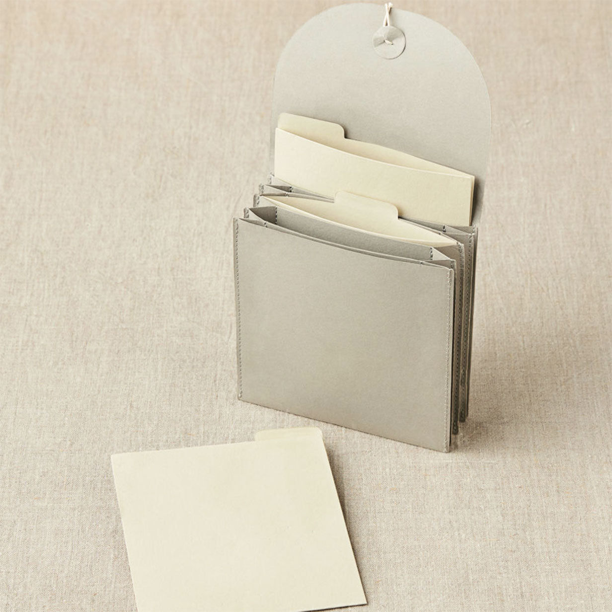 Cocoknits grey coloured paper based miniature expanding file standing on linen background