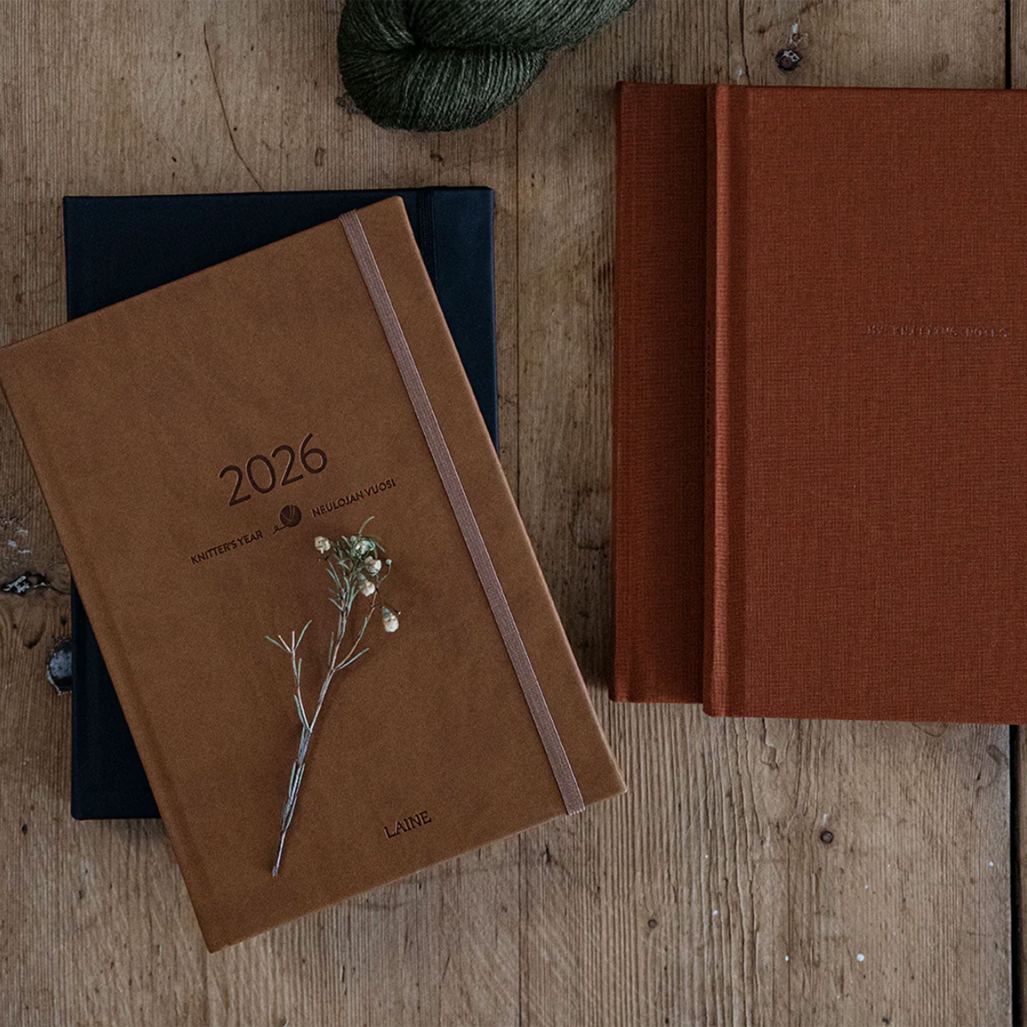 Knitters Year 2026 planner closed showing brown cover placed on top of black closed planner