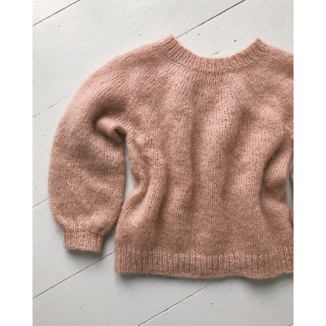 Pink knitted sweater on a light gray floor