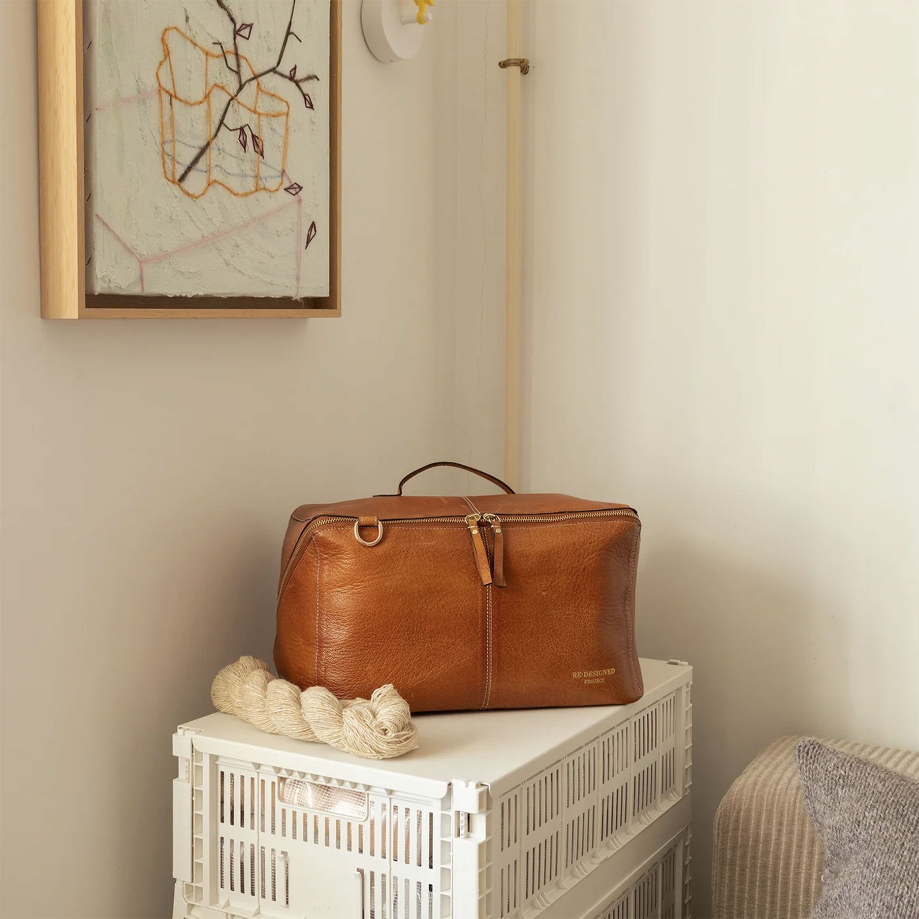 Project 90 brown XL leather organiser bag on a white surface with a neutral wall and decorative elements in the background