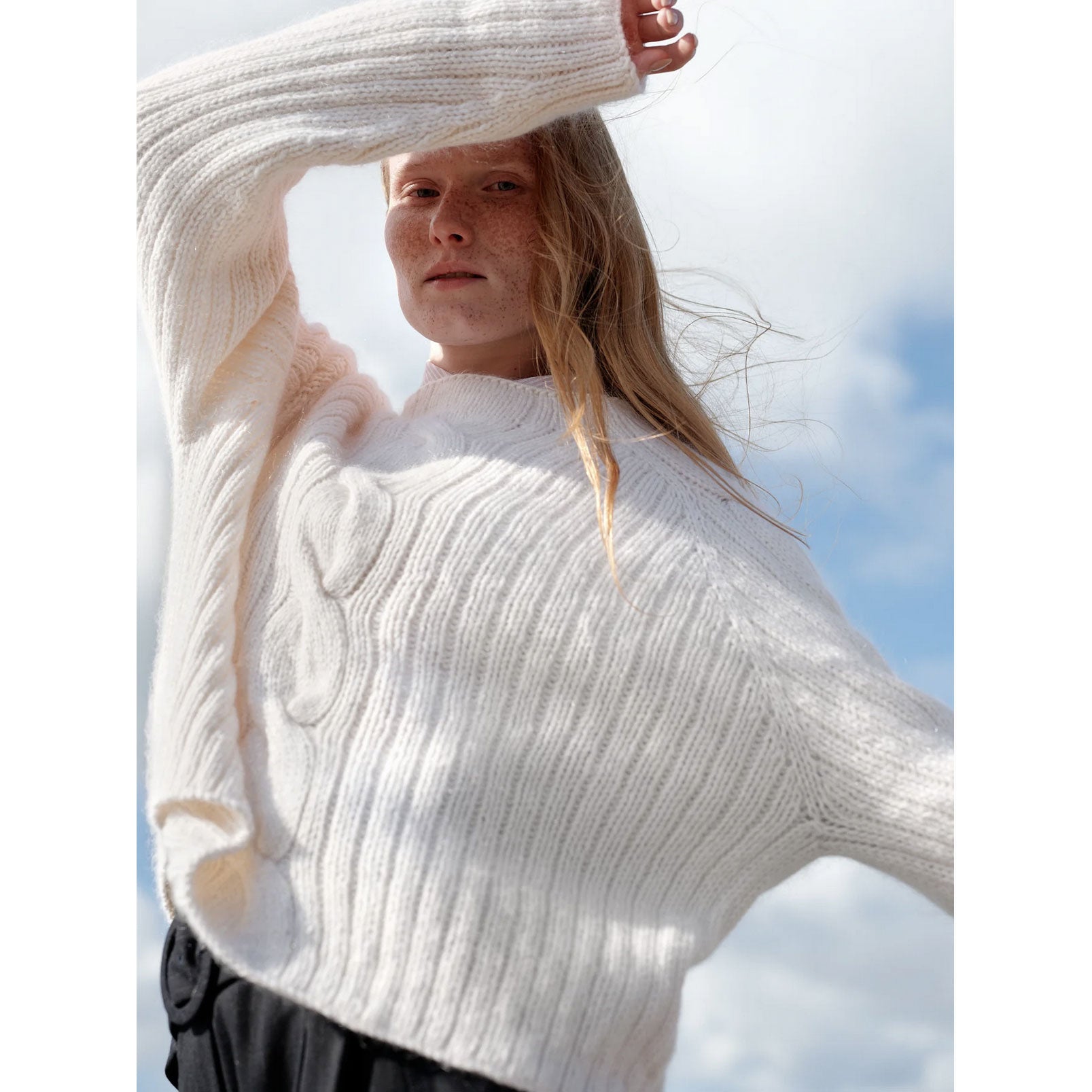 Woman wearing a white sweater with a blurred background
