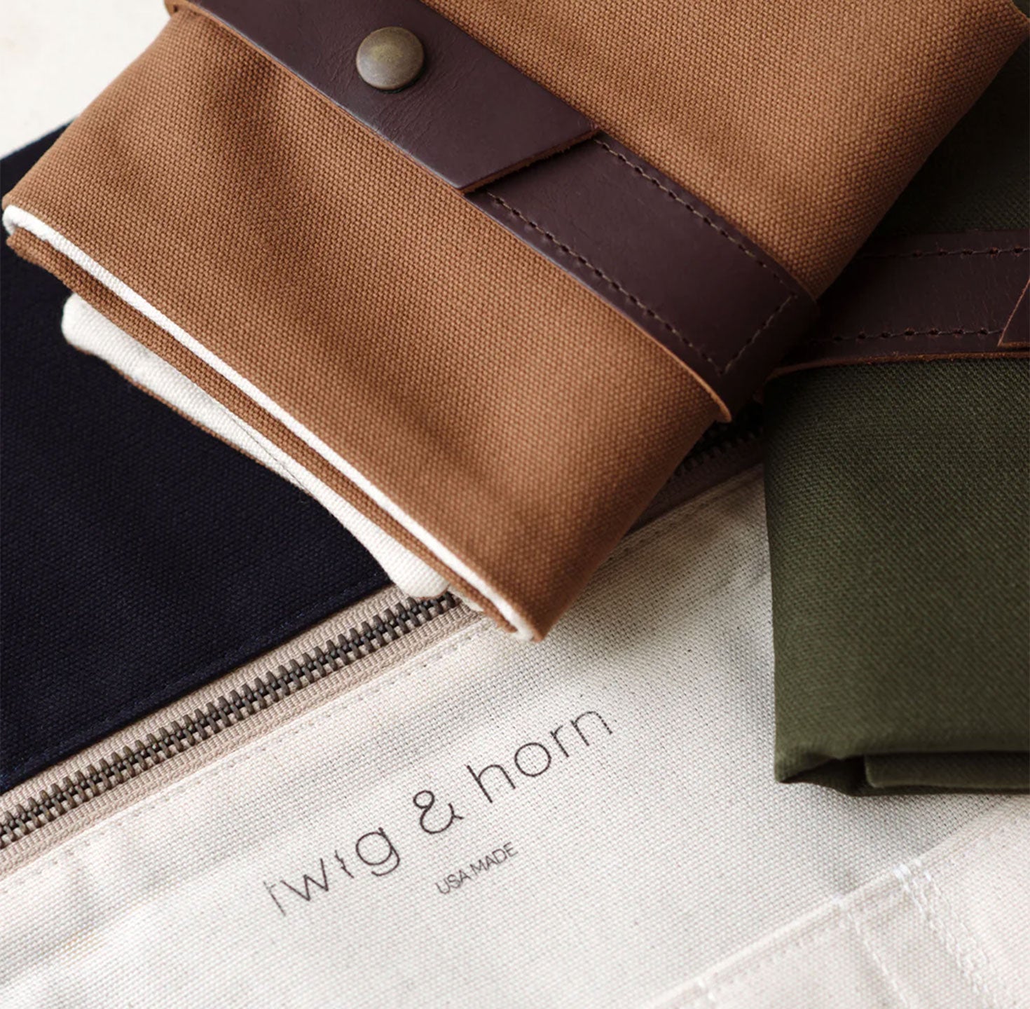 Camel brown and olive green canvas fabric cases Twig & Horn branding on a white surface