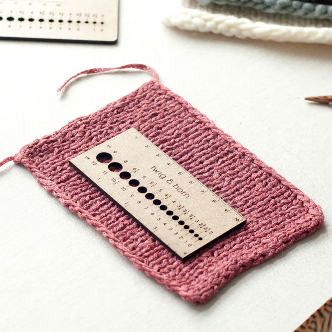Twig & Horn MDF small ruler gauge placed on sample of pink stocking stitch at an angle