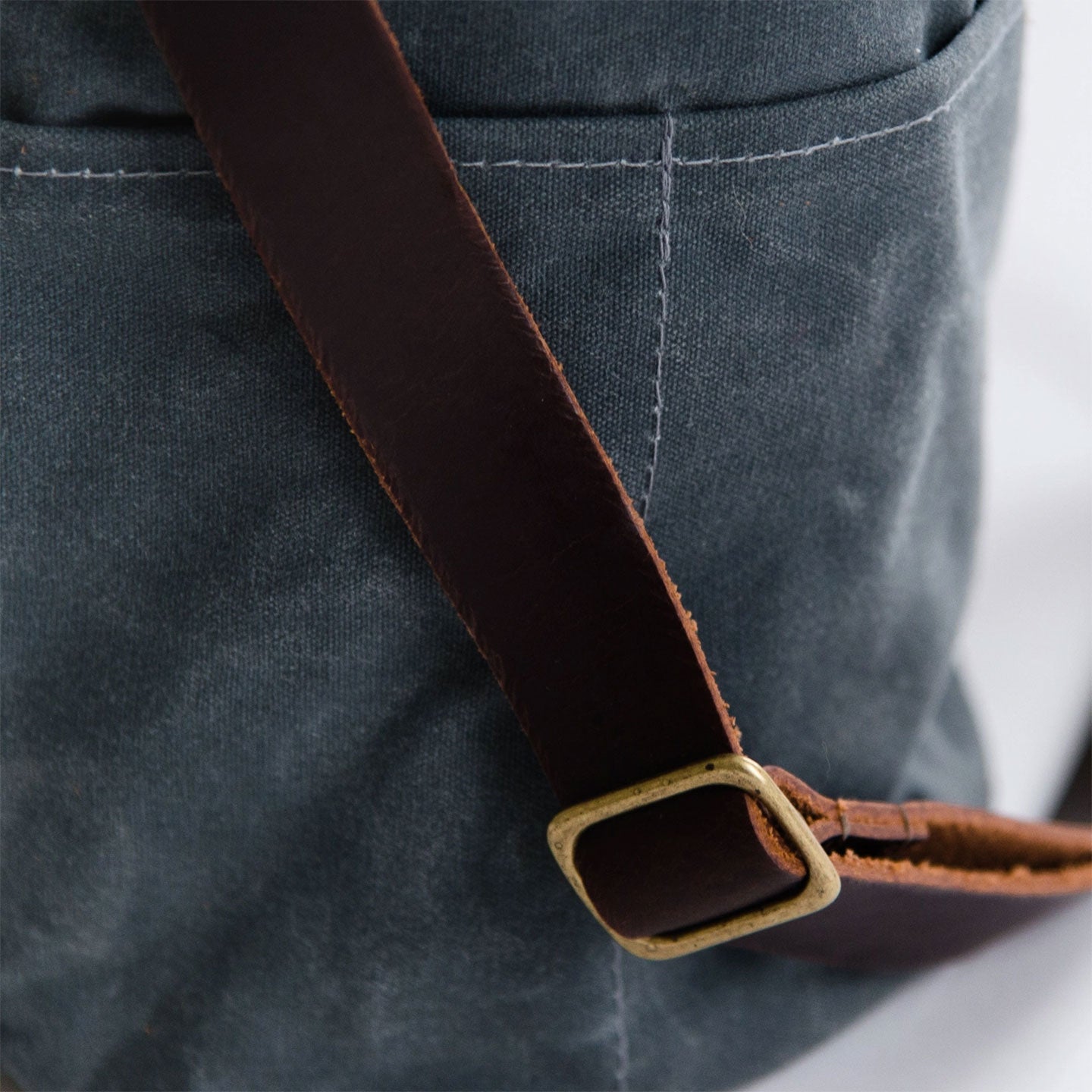 Close up of leather bucket bag strap with brass bucket