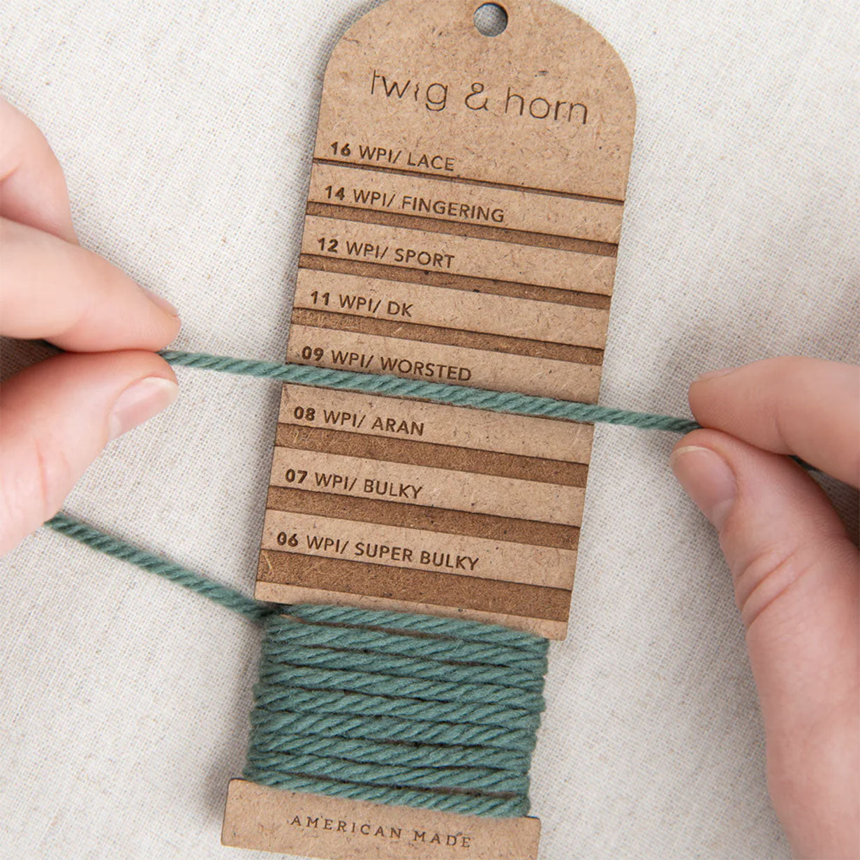 Person using a yarn WPI tool with 'Twig & Horn' branding on a textured surface.