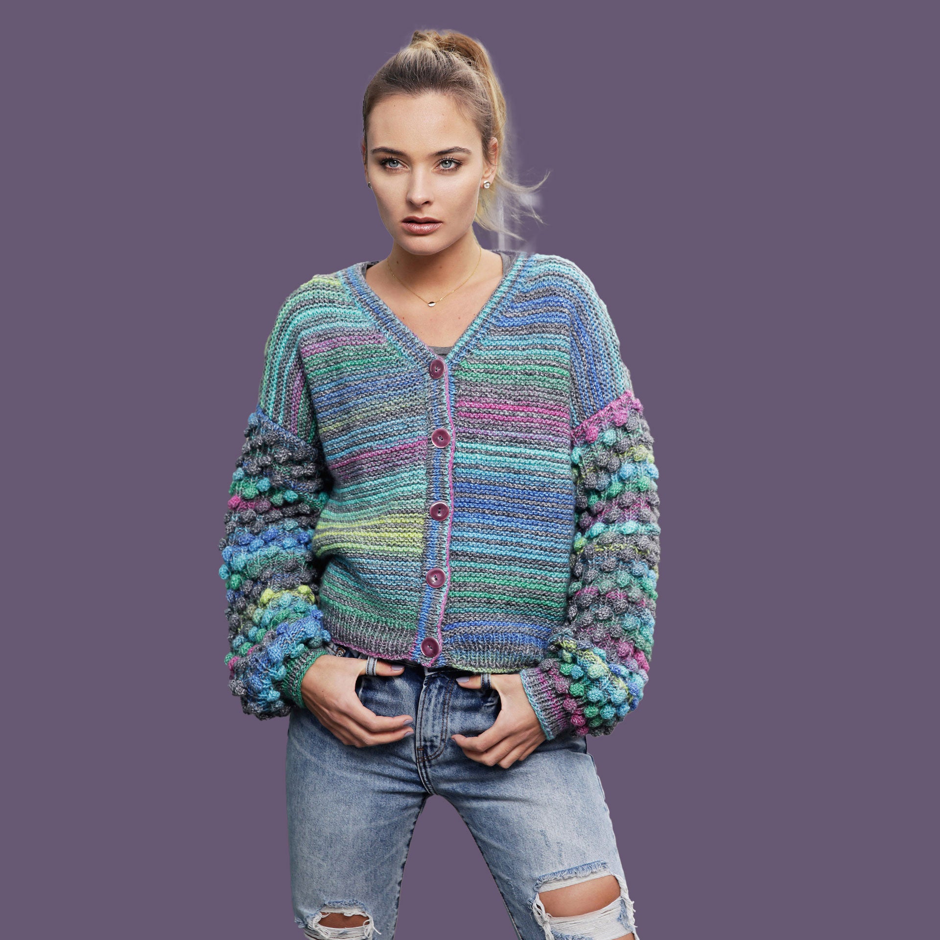 Woman wearing a colorful knitted cardigan against a purple background