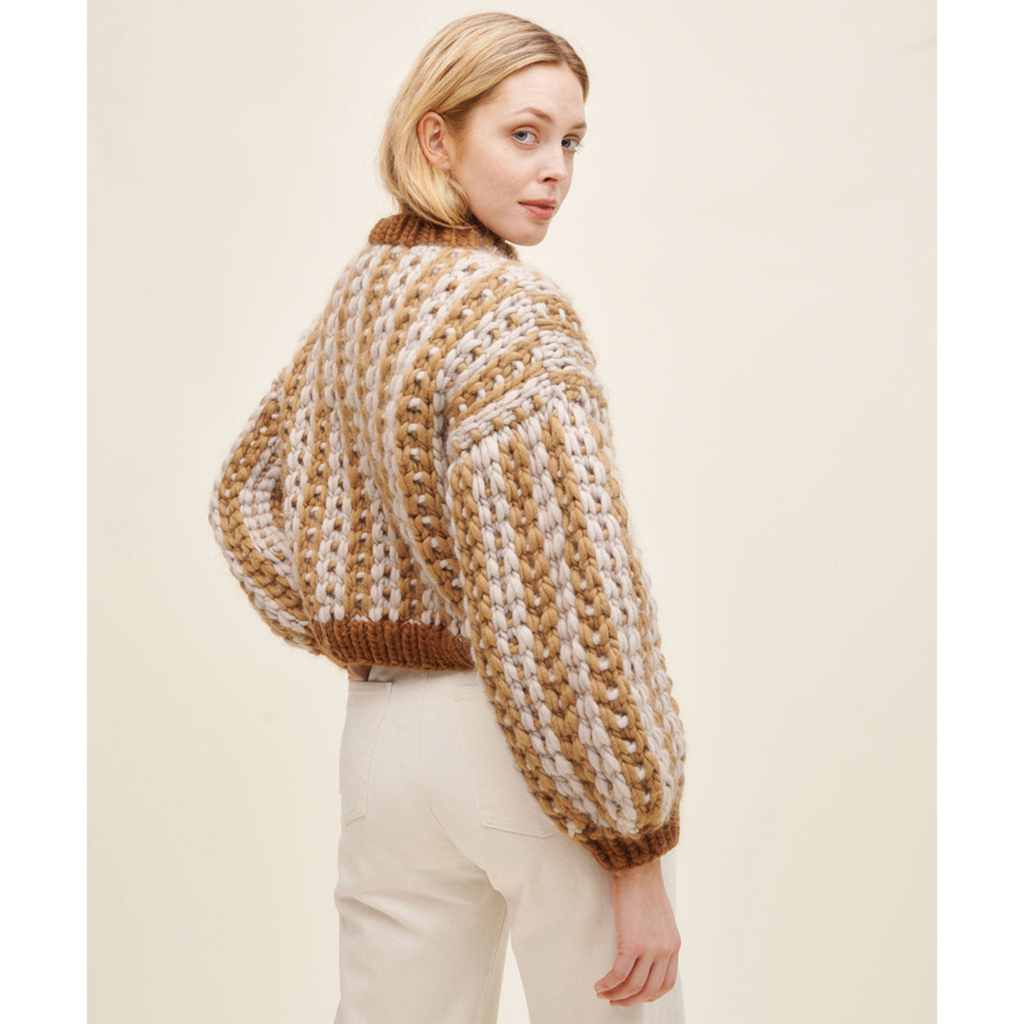 Woman wearing knitted sweater in mosaic stitch, vertical stripes of caramel and cream with darker brown hem, cuff and neck (09 Snow and Tell)
