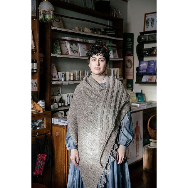 Windgate by Fiona Alice. Woman wearing a patterned shawl in a room with bookshelves and decor.