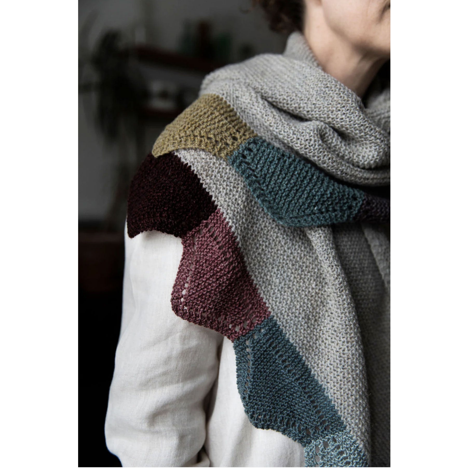 Person wearing a multicolored knit scarf with a blurred background