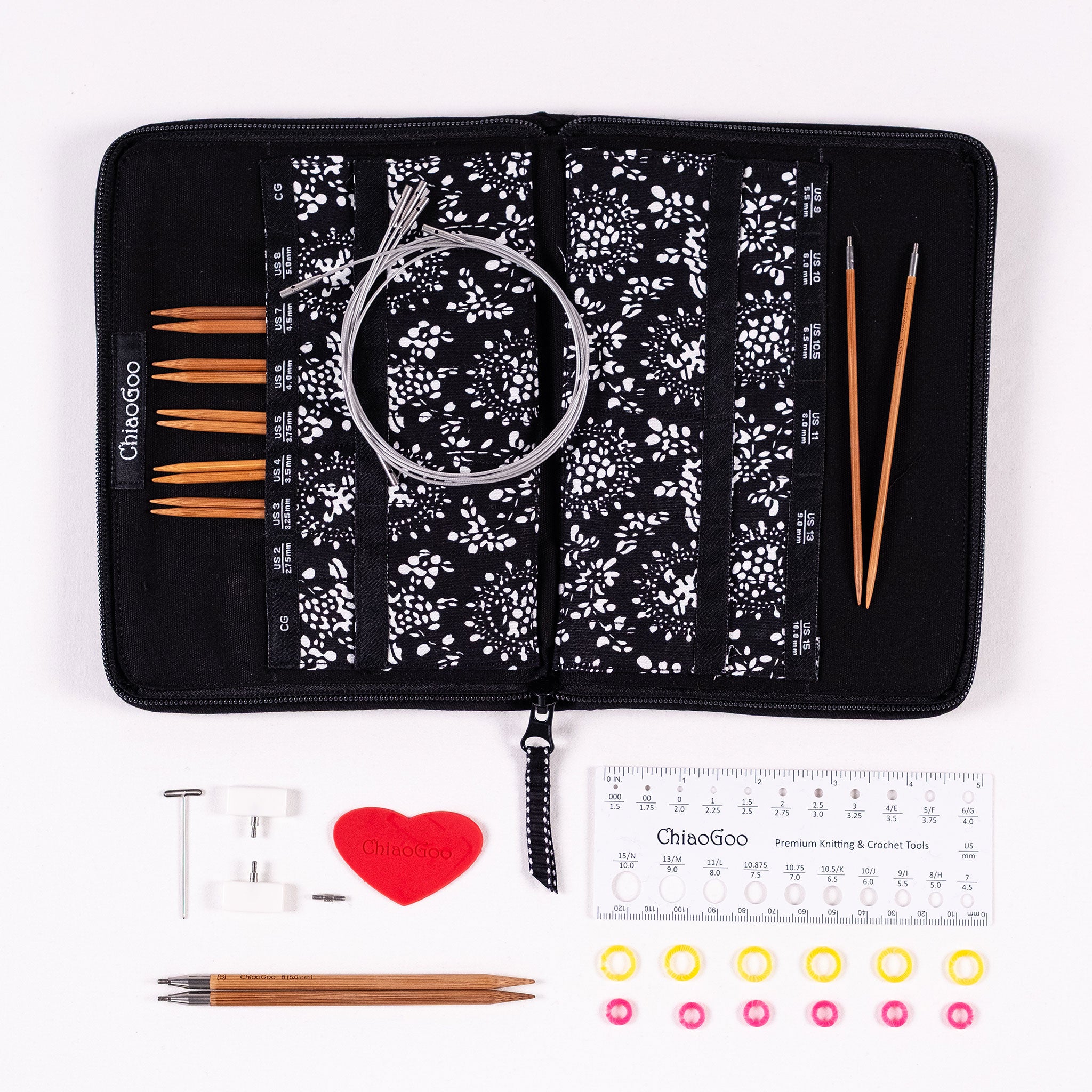 ChiaoGoo SPIN bamboo interchangeable knitting needle set with black zippered fabric case, 5in long bamboo needle tips, silver coloured SWIV360 cables, heart-shaped rubber gripper, tightening key, two white end stoppers, a small cable connector, 5in ruler gauge, six yellow and six pink stitch markers on a white background