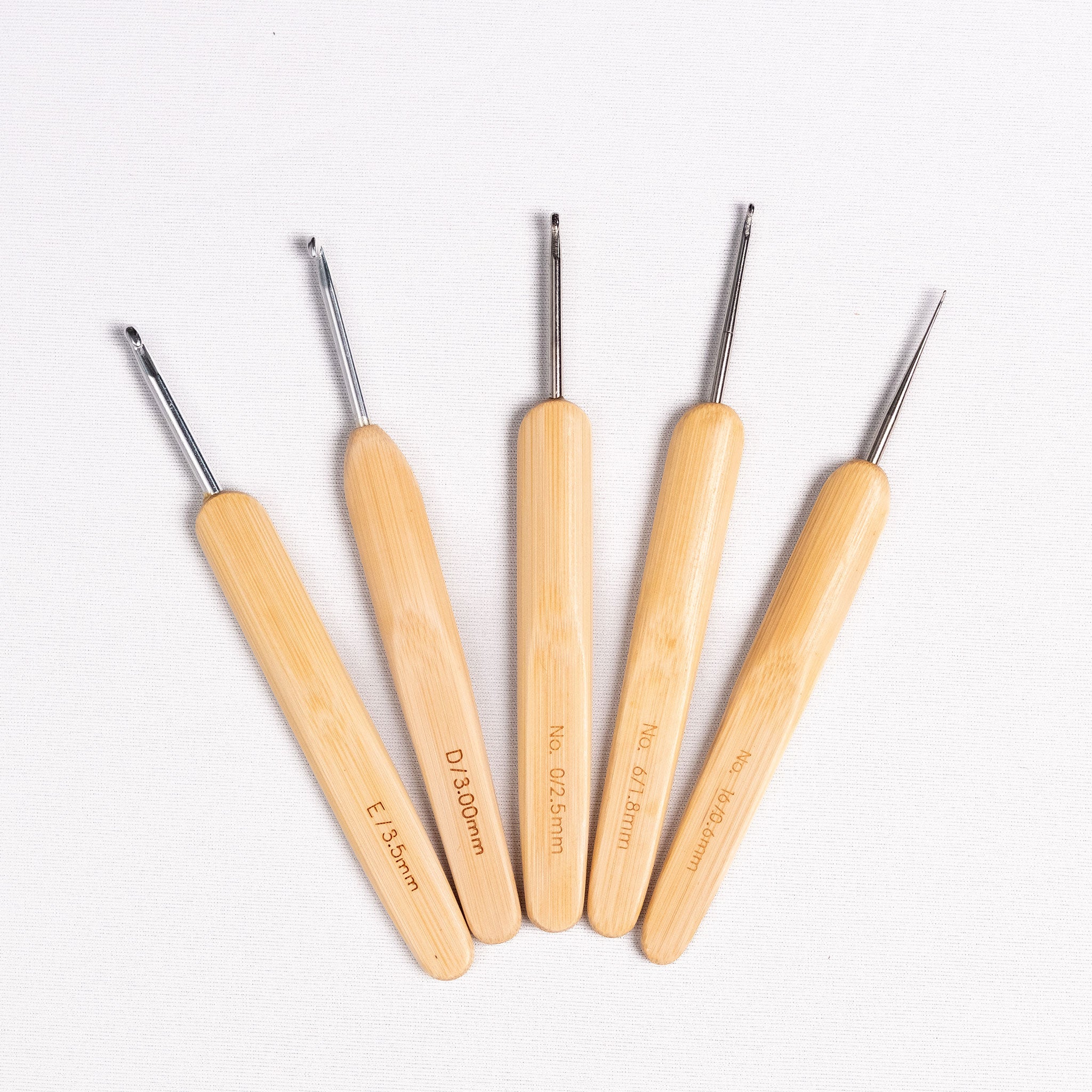Set of five ChiaoGoo bamboo handled crochet hooks with metal heads on a white background