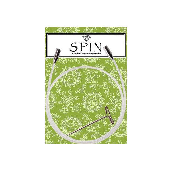 Product packaging for SPIN interchangeable knitting needle cable, a clear nylon cable with stainless steel connectors placed on a green floral patterned background