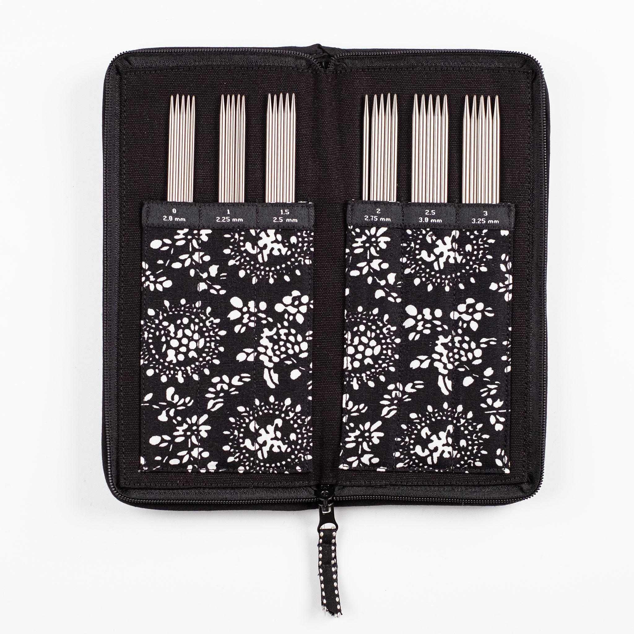 Set of six sets of stainless steel DPNs in a labelled fabric black case with floral pattern on a white background