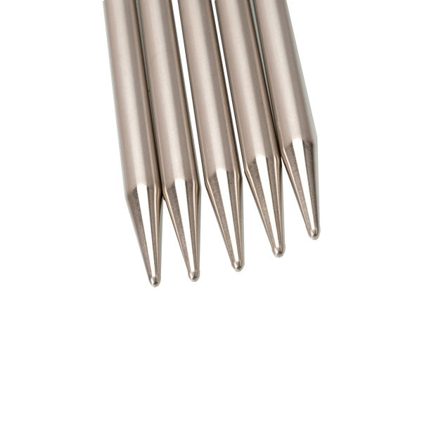 Close-up of five stainless steel knitting needle tips on a white background