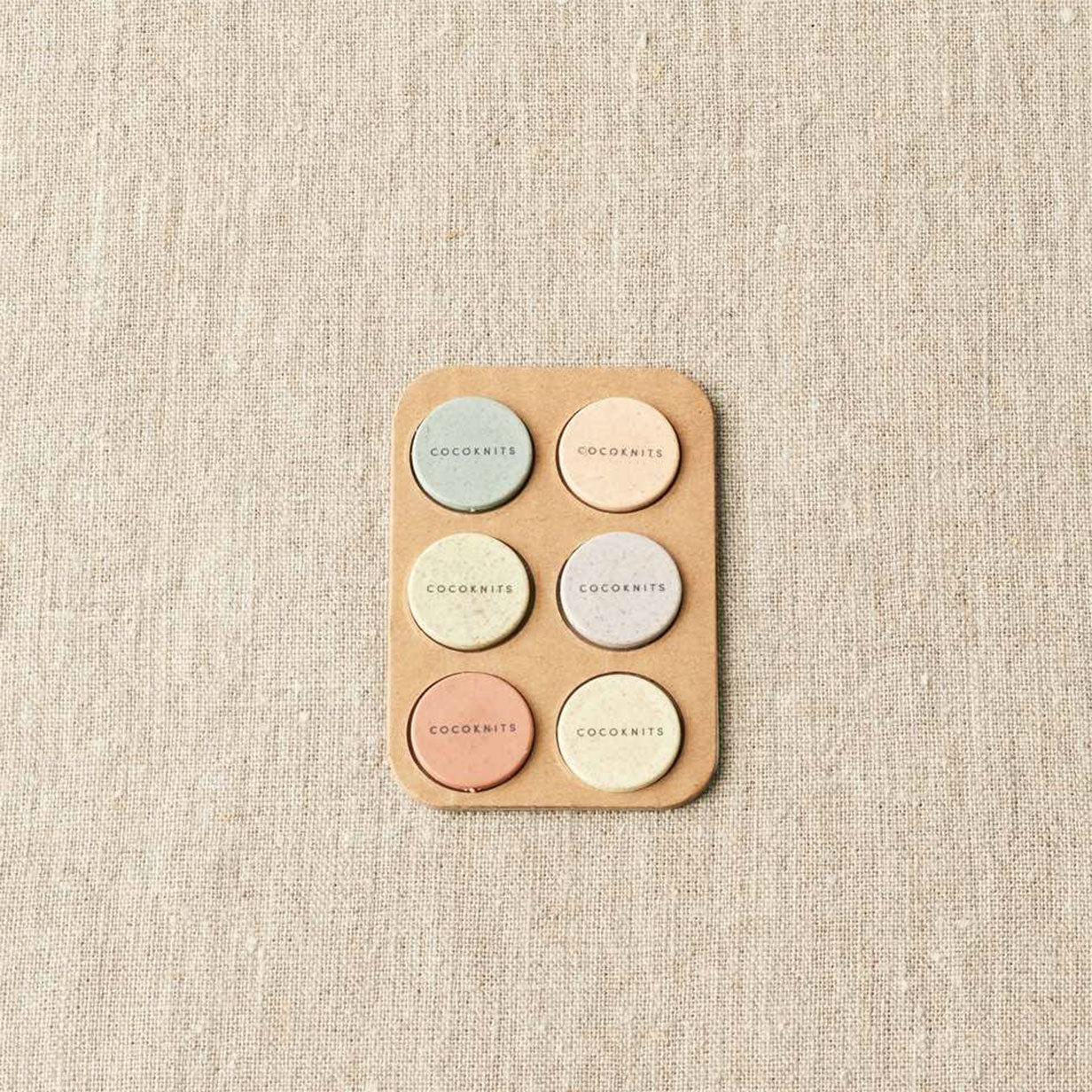 Set of six colourful magnets in two columns of three on linen background