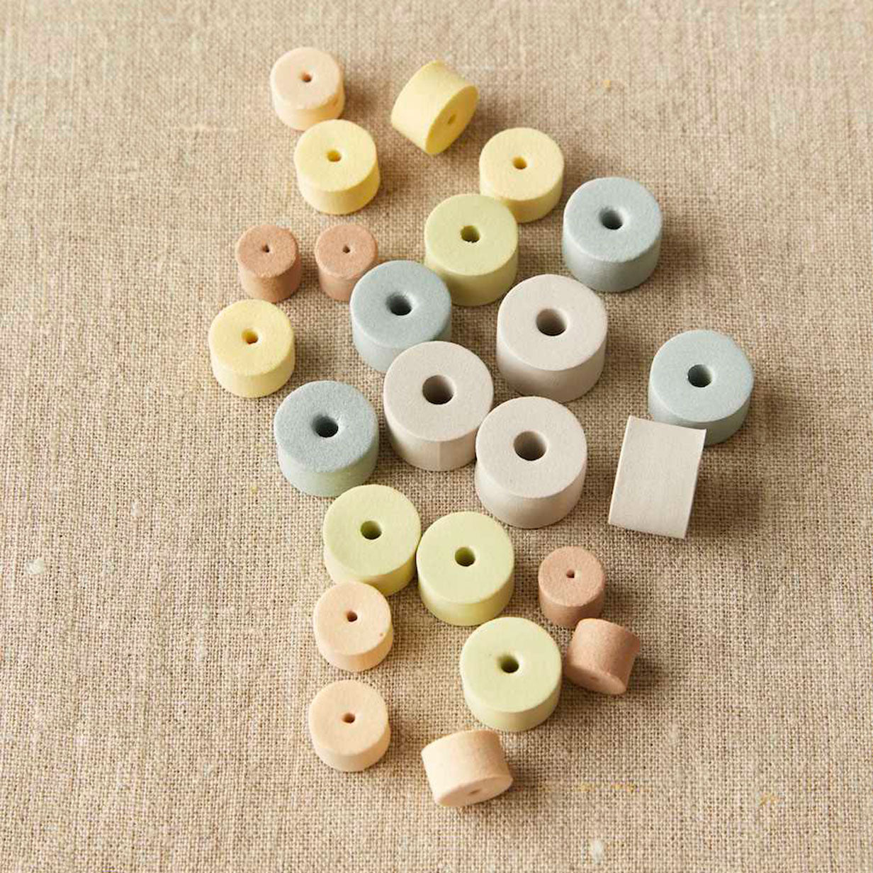 Earth tone EVA foam stitch stoppers on a linen cloth