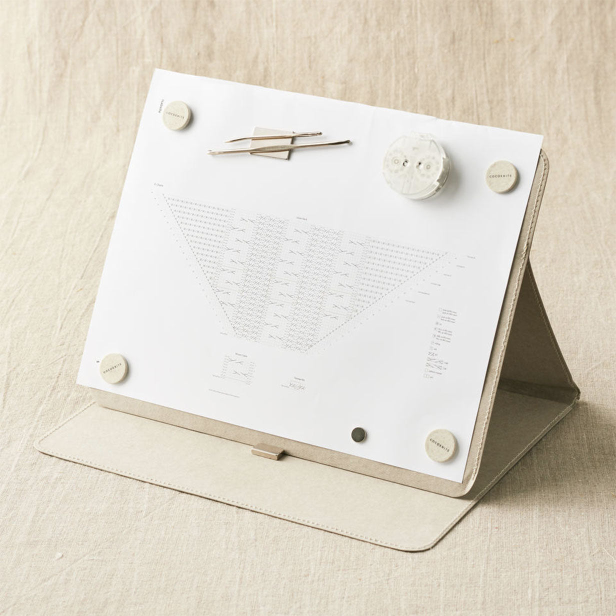 Cocoknits grey Makers Board in use showing row counter stuck to face, stitch saver and tapestry needle stuck to oblong magnet