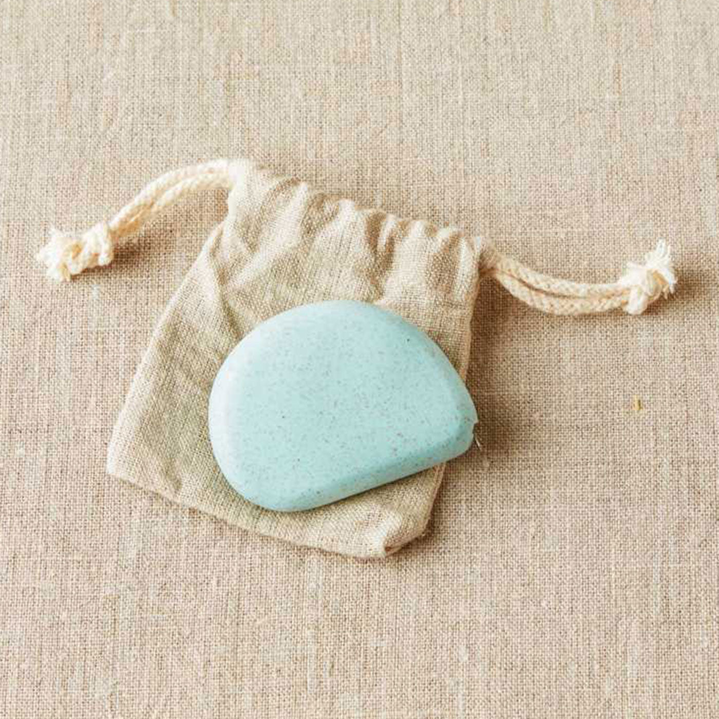 Pale blue coloured pebble shaped tape measure on linen drawstring bag