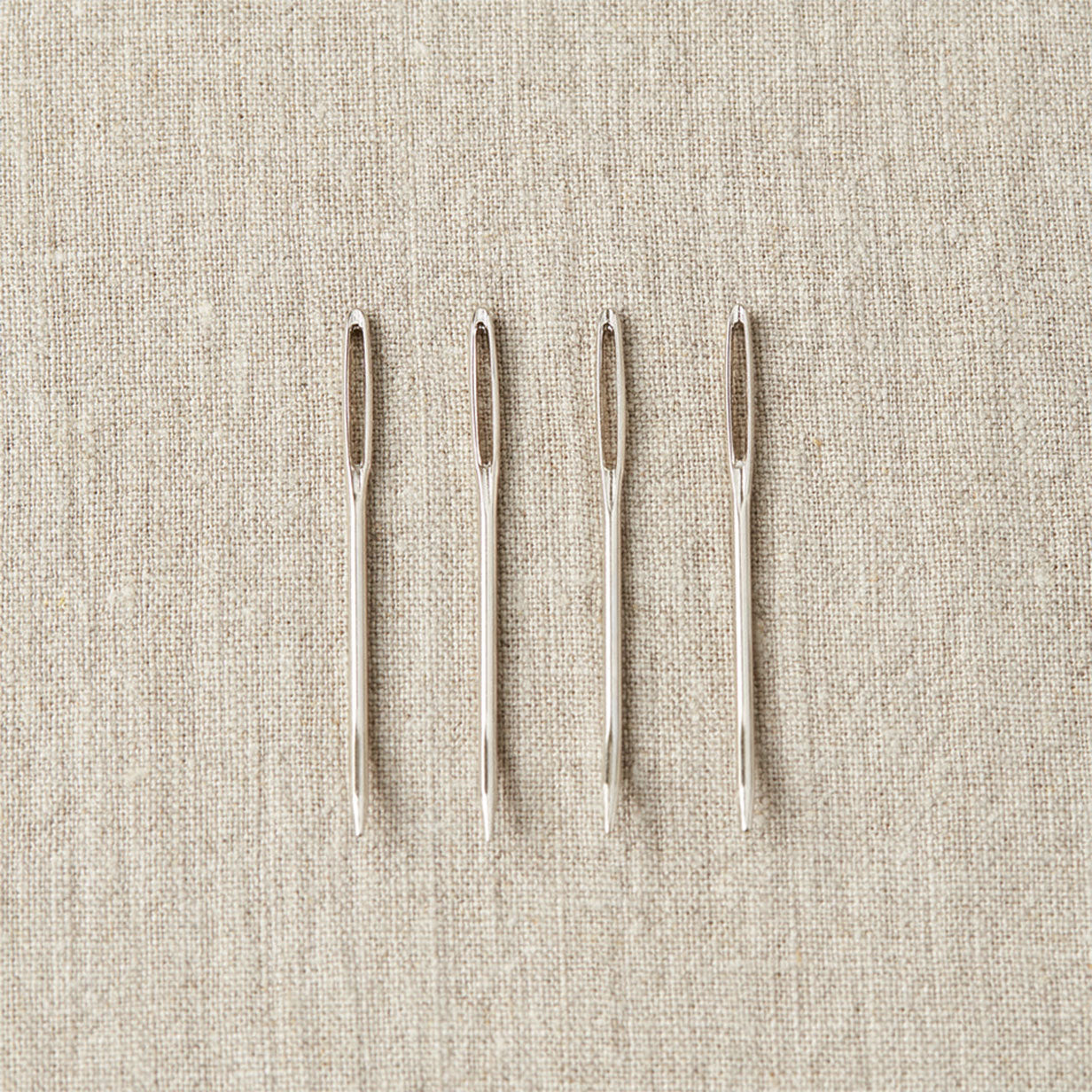 Four stainless steel sewing needles with bent tips and additional eyes in the tips