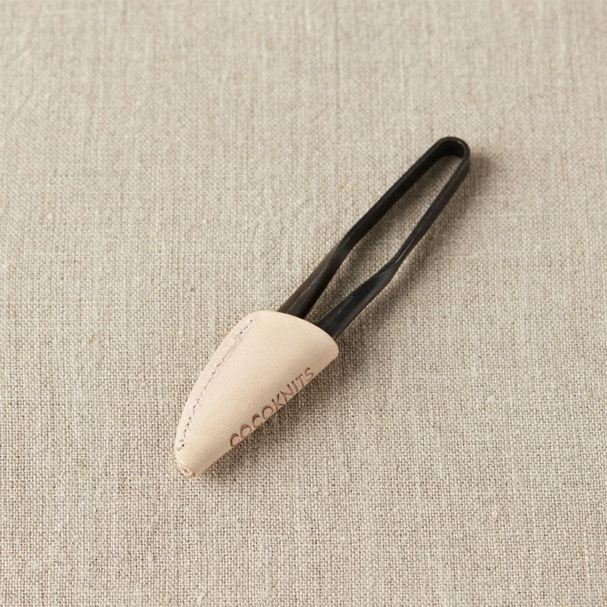 Closed yarn snips with a black handle with blades closed and covered by leather protector with COCOKNITS logo