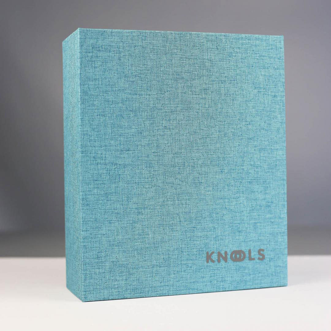 Turquoise needle garage folder with KNOOLS logo standing closed on a white surface