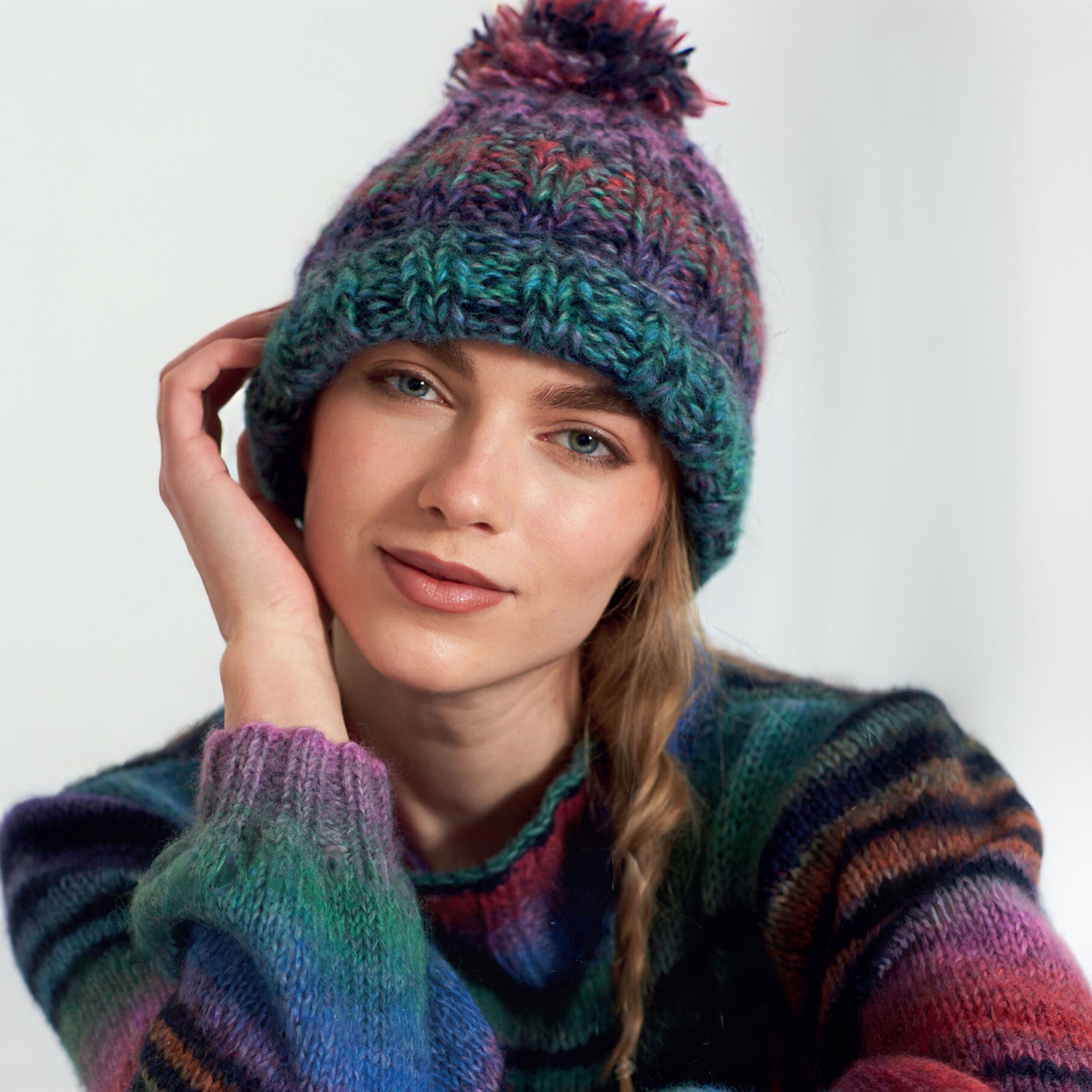 Woman wearing a colorful knitted hat and sweater against a white background