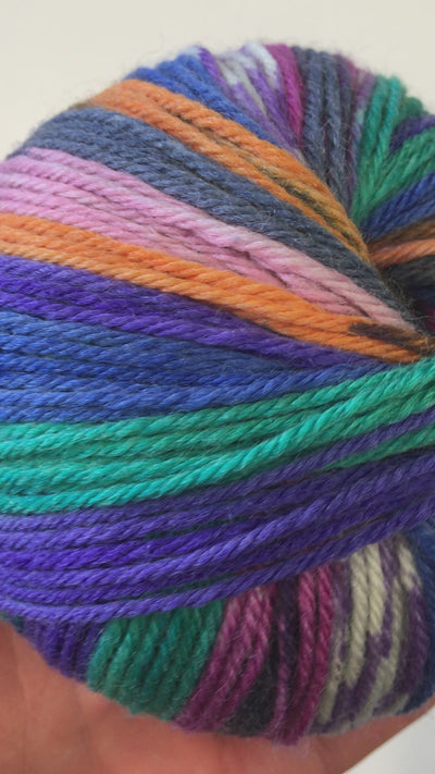 Video closeup of colourful single ball of KnitCol, violet, turquoise, orange, pink, teal