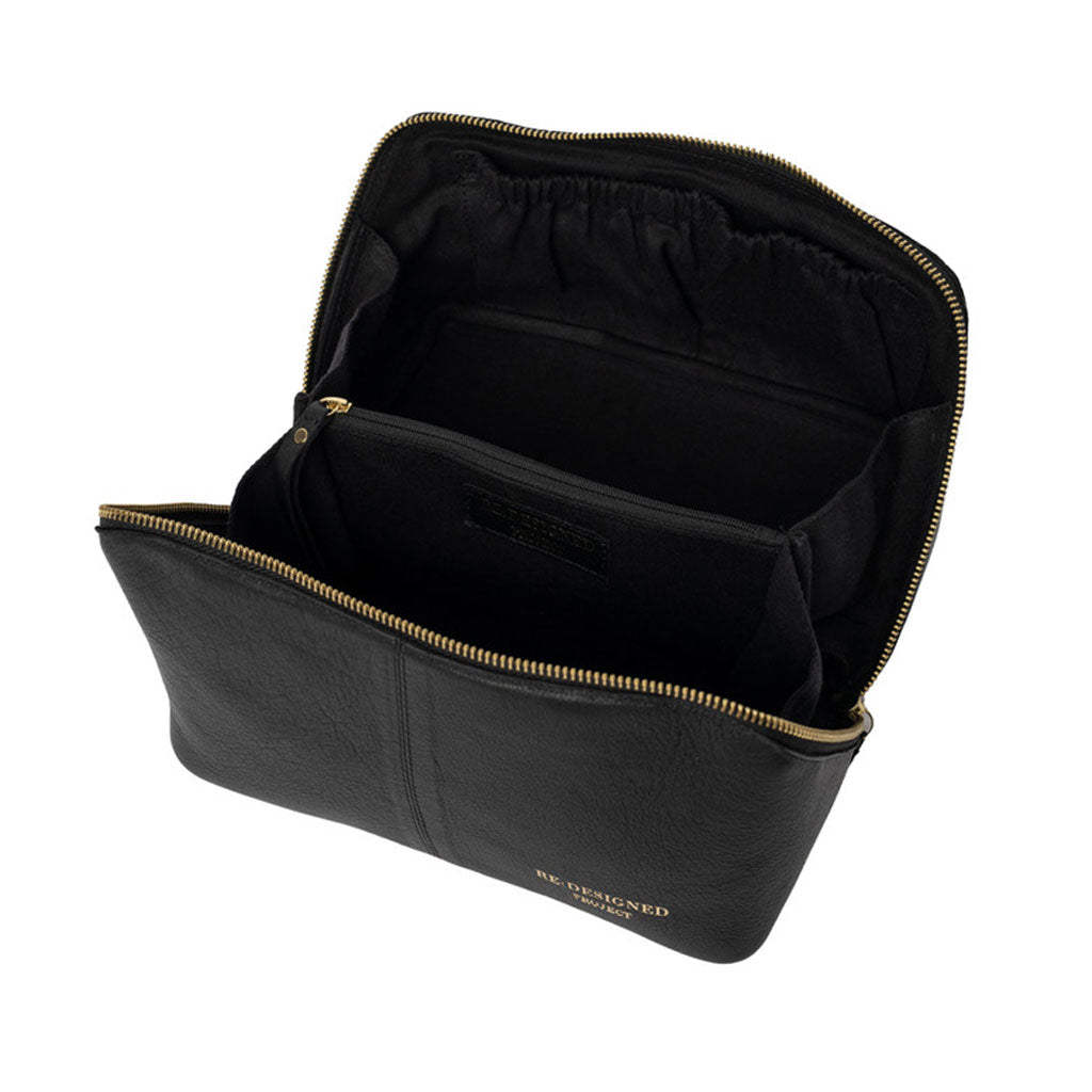 Interior of black leather clutch bag with central divider zipped pocket gold zipper on a white background