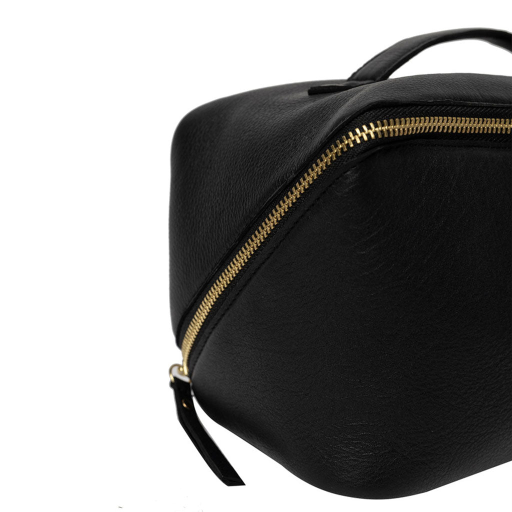 Close up of gold coloured zipper on black leather project bag on a white background