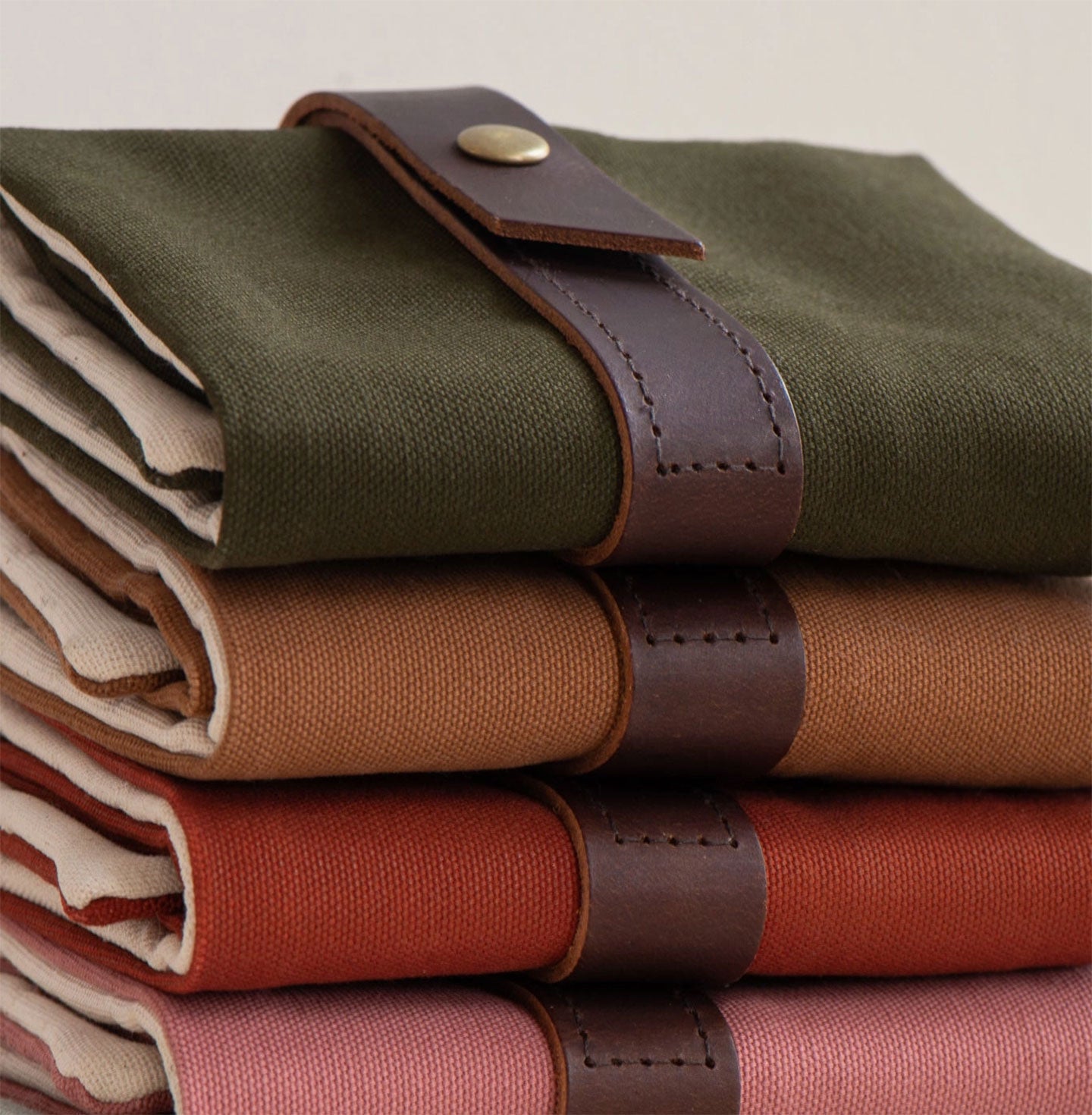 Pile of canvas interchangeable knitting needle cases with leather fastening strap