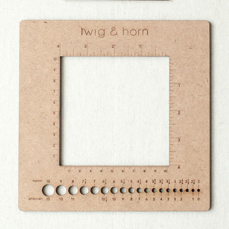 Twig & Horn MDF square gauge ruler with centimetres and inches mark around a 4in square cut out, metric/US knitting needle size holes across bottom panel